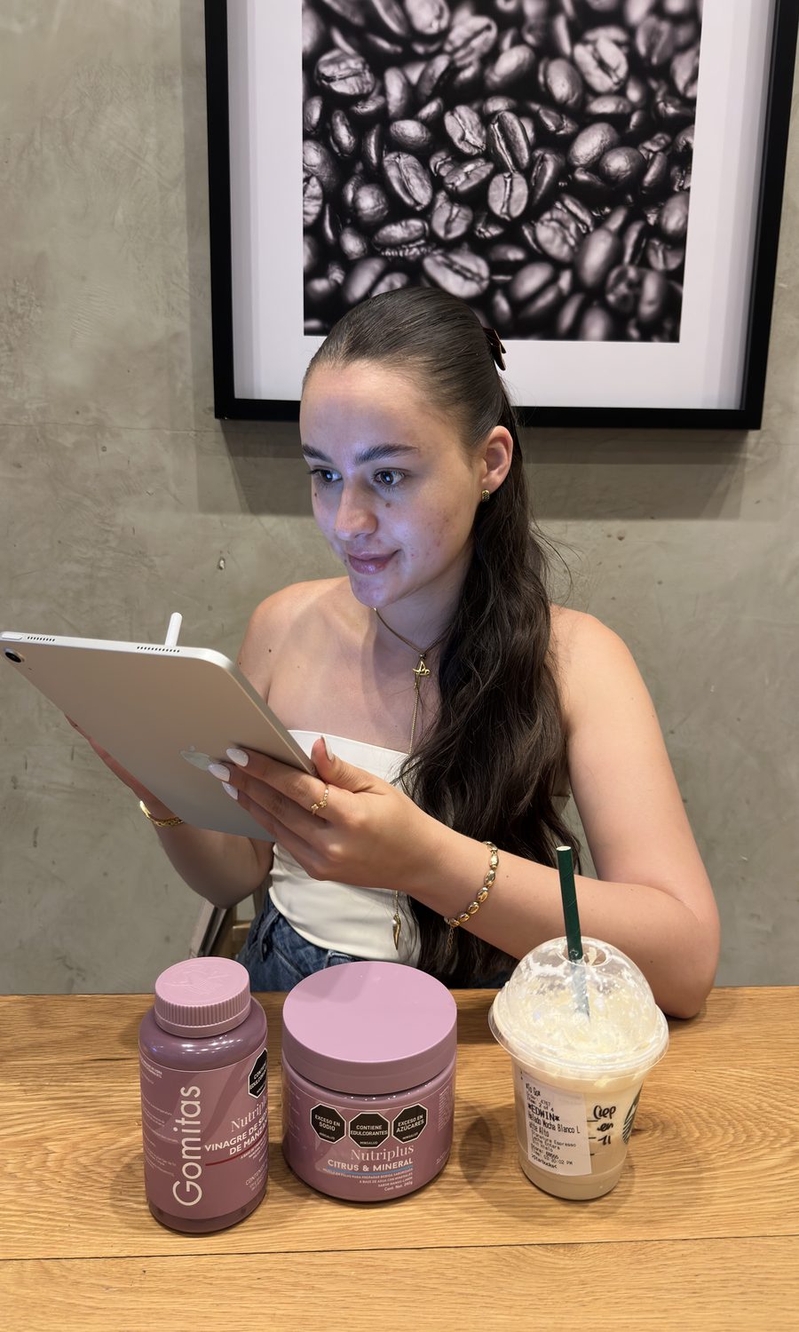 Eli trabajando con la tablet en una cafetería, con productos Nutriplus sobre la mesa